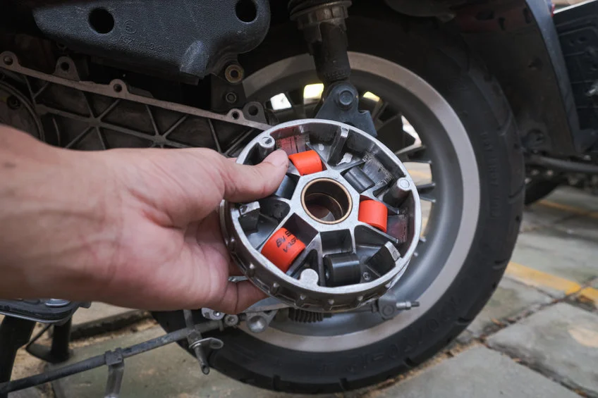 Roller berwarna merah dan hitam terlihat pada rumah variator yang dipegang dengan tangan.